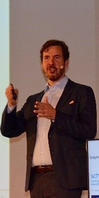Prof. Stefan Galka von der OTH Regensburg erläutert die Vor- und Nachteile unterschiedlicher Steuerungskonzepte für Routenzüge auf dem 11. Kooperationsforum „Schlanker Materialfluss“ am 14. November 2018 in Regensburg.