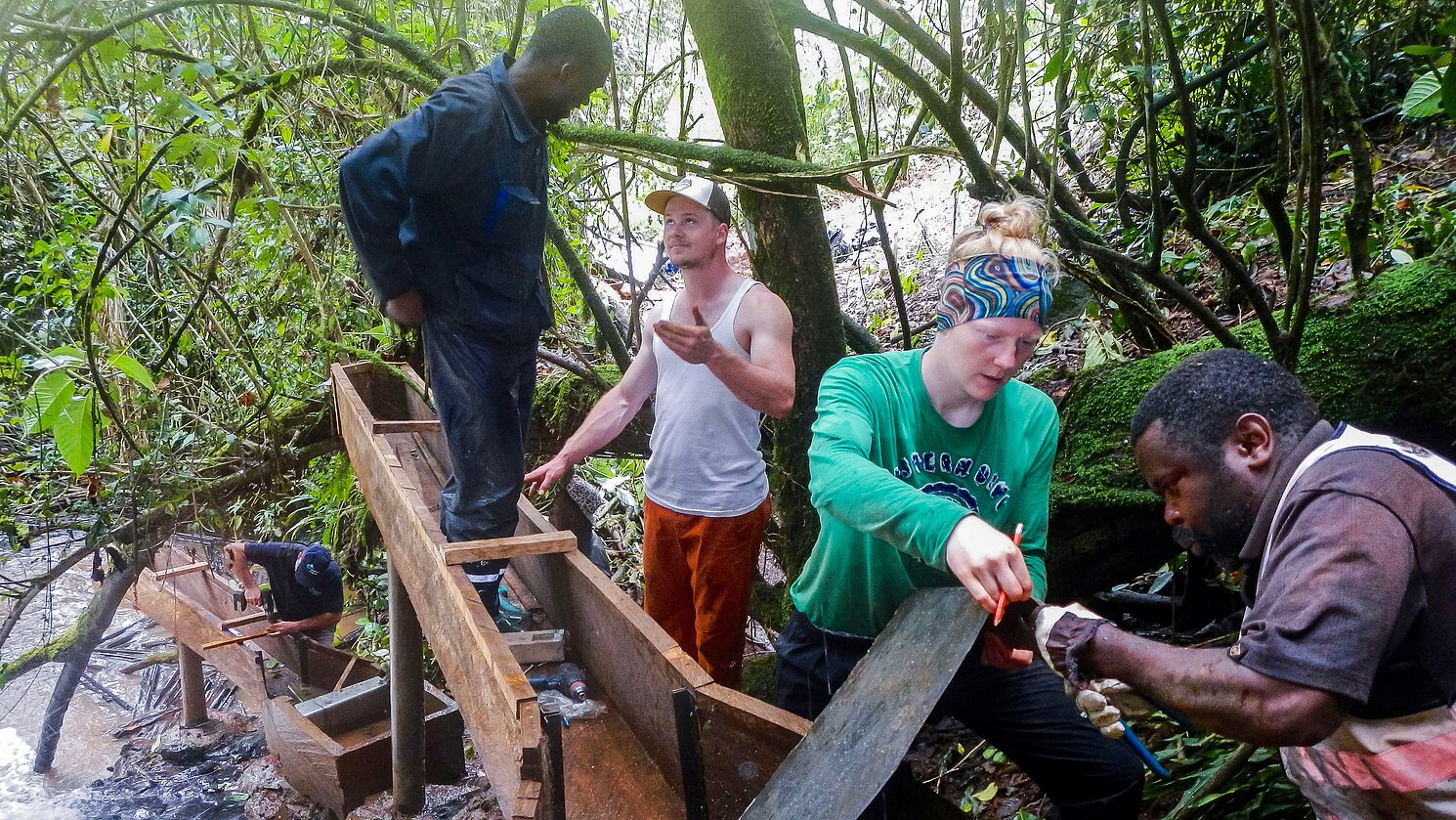 Zwei Regensburger Studierende und lokale Fachkräfte in enger Zusammenarbeit, um die Turbineninstallation zu realisieren.