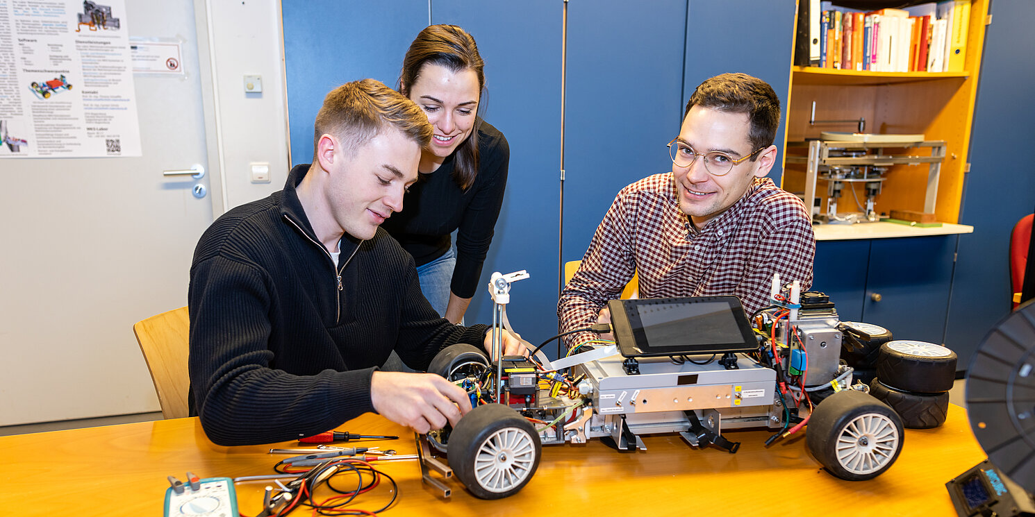 Drei Studierende im Labor MKS arbeiten an einem Modellauto