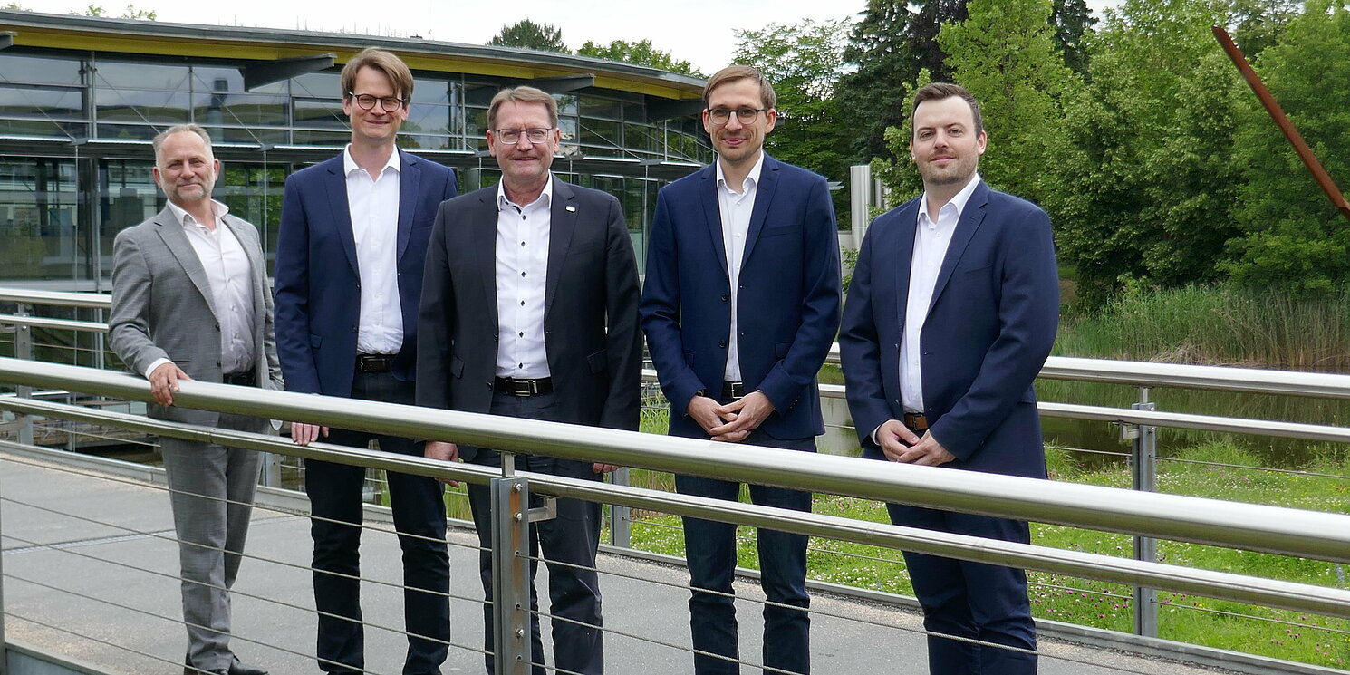 Fünf Männer stehen auch einer Brücke und schauen zur Kamera.