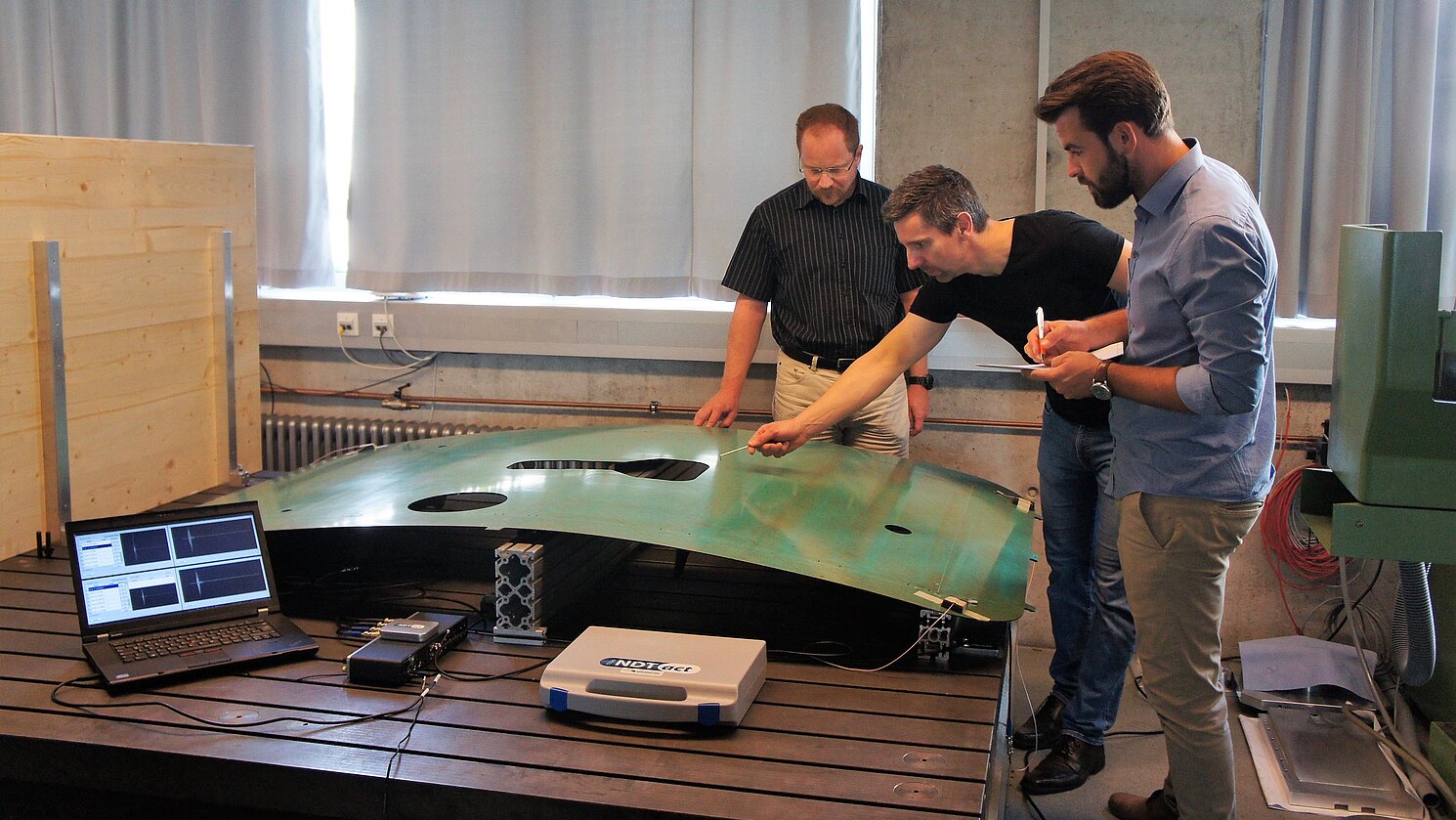 Von links: Prof. Dr.-Ing. Ingo Ehrlich (Leiter Labor für Faserverbundtechnik), Dr. Raino Petricevic (Technischer Geschäftsführer der Firma iNDTact) und Matthias Schlamp (Projektmanager BIRD) am Messaufbau der abschließenden Bauteilversuche im Projekt BIRD