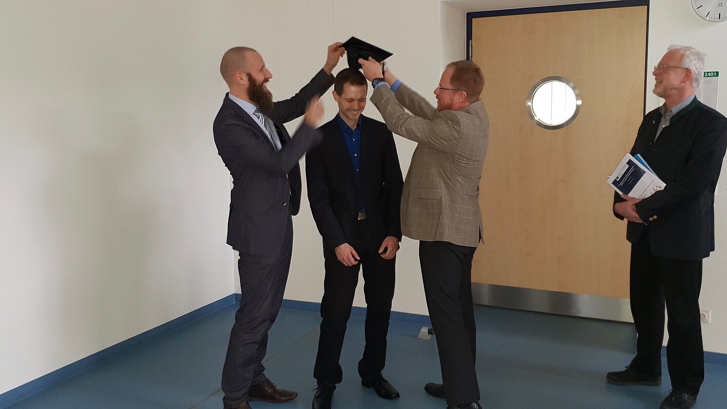 Von links: Prof. Dr. Sebastian Dendorfer, Michael Putzer und Prof. Dr. Ingo Ehrlich bei der Überreichung des Labor-Doktorhuts, dies allerdings nur leihweise, denn dieser Hut ist ein Ausstellungsstück im Schaukasten des Labors Faserverbundtechnik.